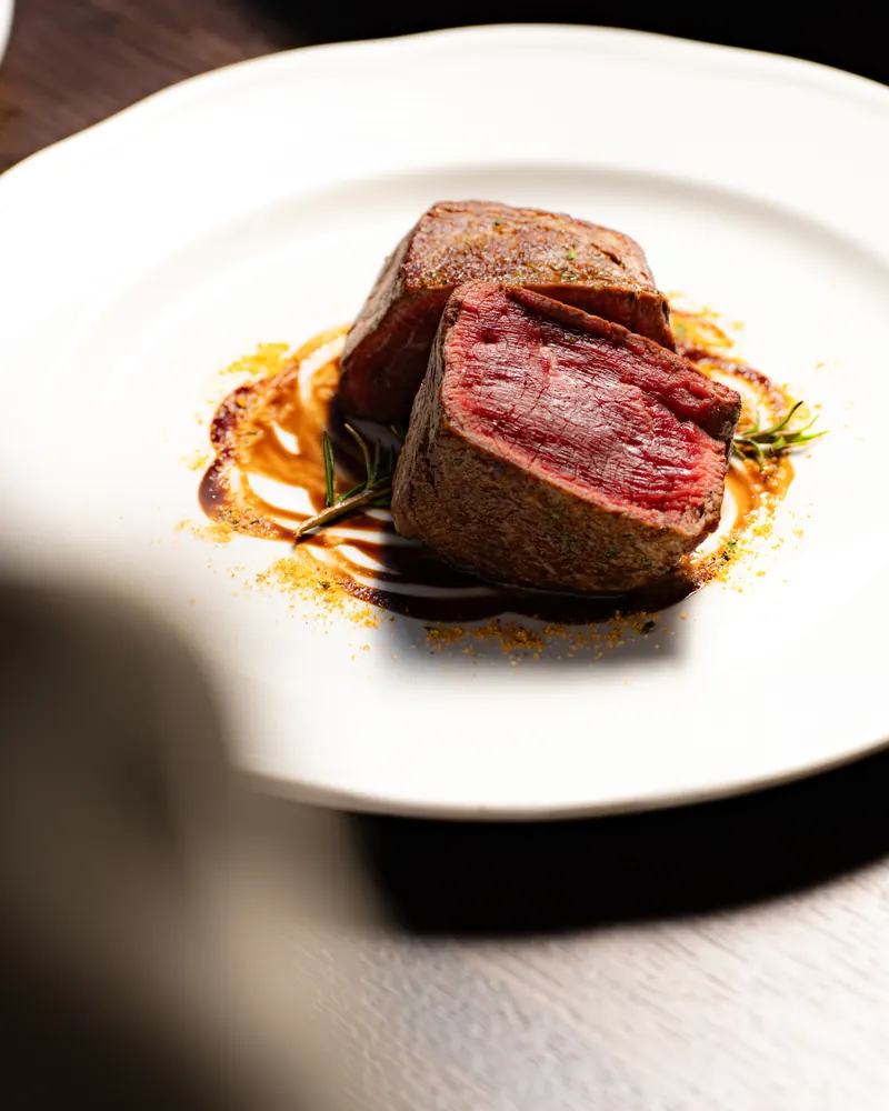 Grilled beef fillet, cut to show its pink centre, on a jus with rosemary
