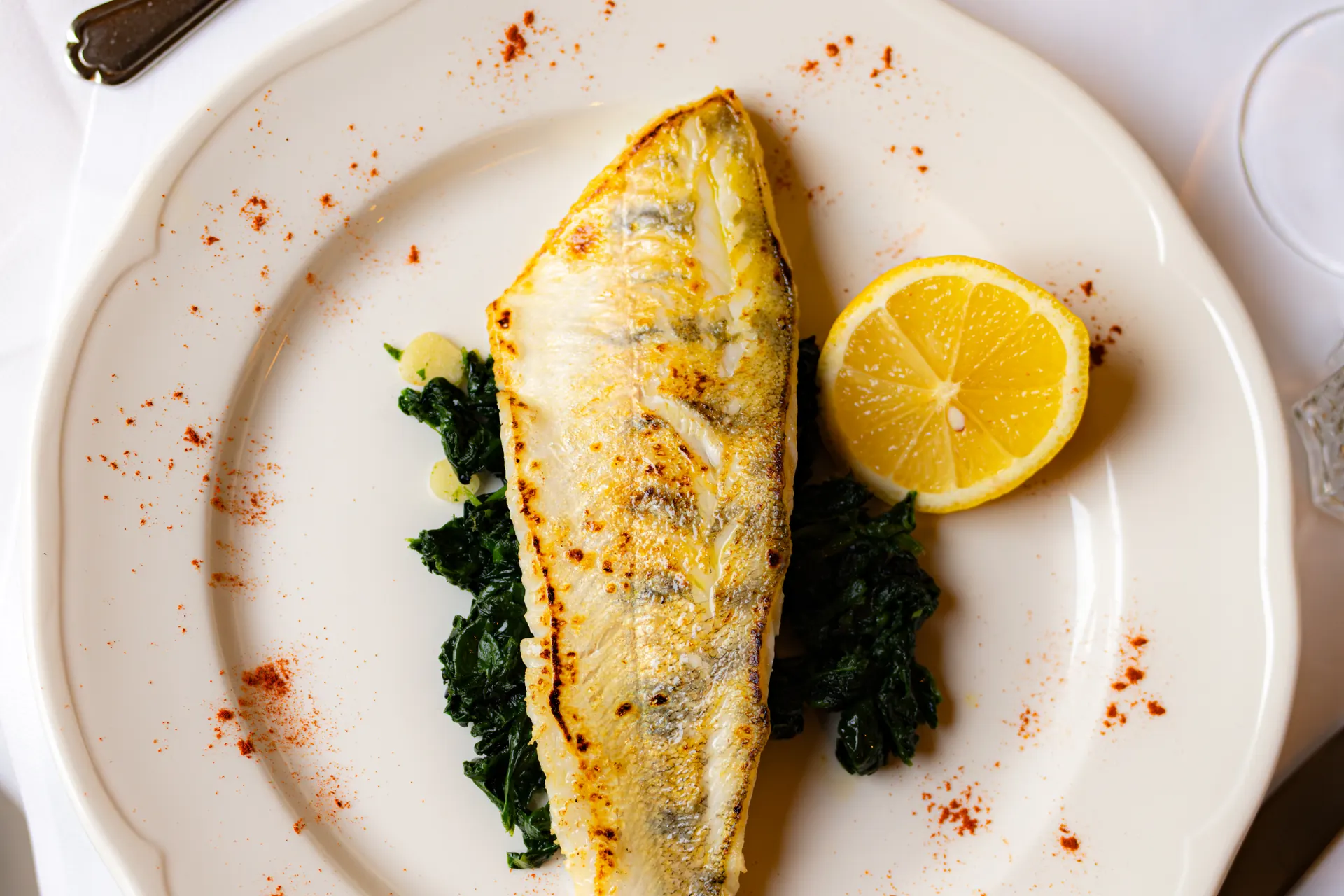 Pan-fried fish fillet on leaf spinach with lemon
