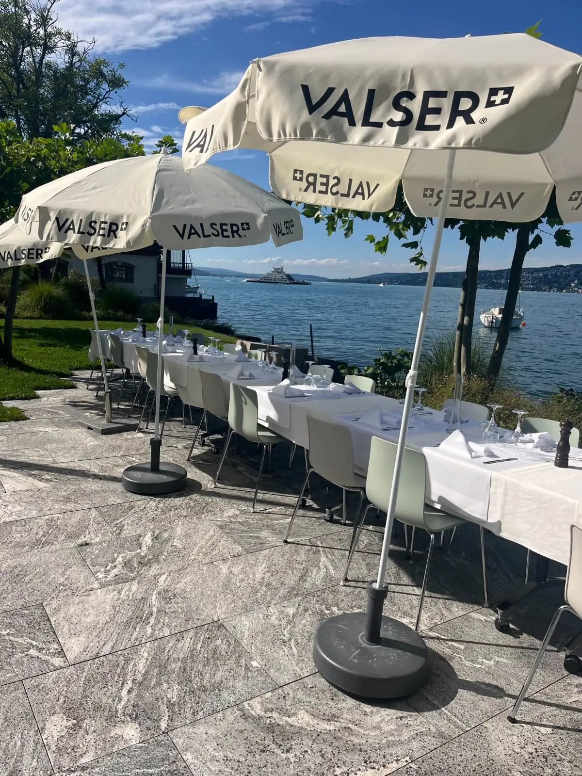 Long table under cream parasols on the lakeside terrace